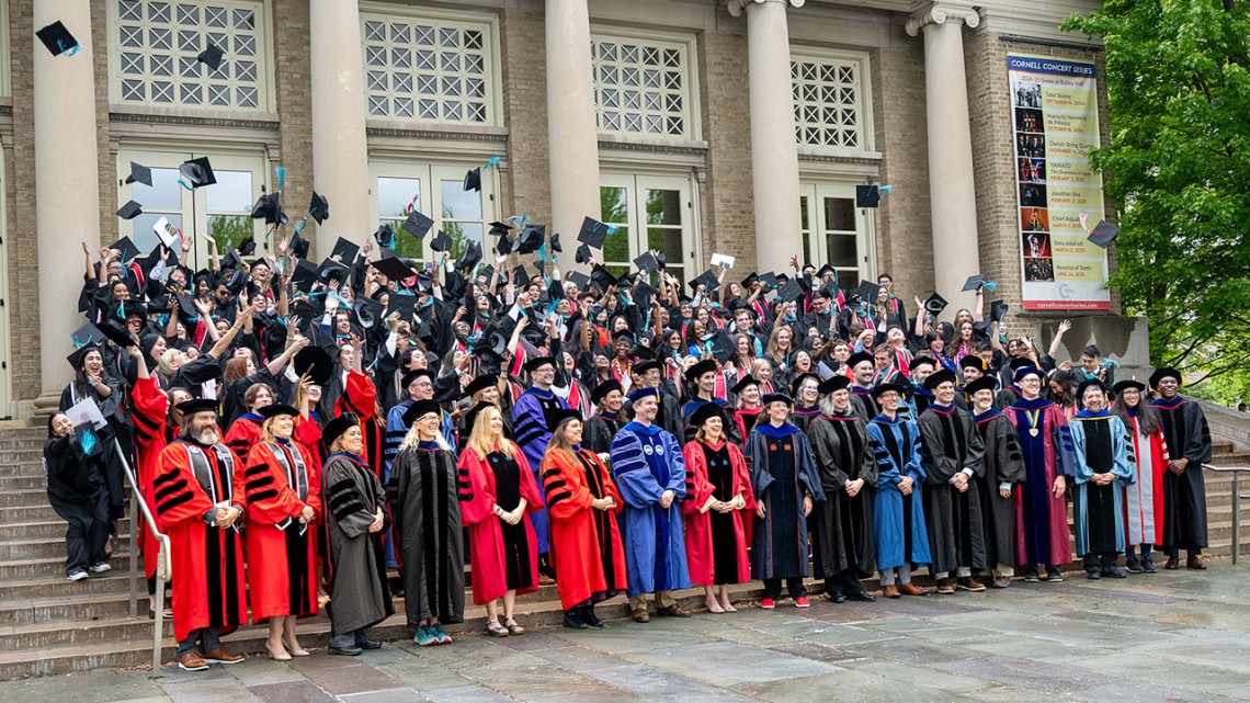 Faculty and graduates of the Cornell Jeb E. Brooks School of Public Policy mark the moment with a celebratory hat toss outside Bailey Hall